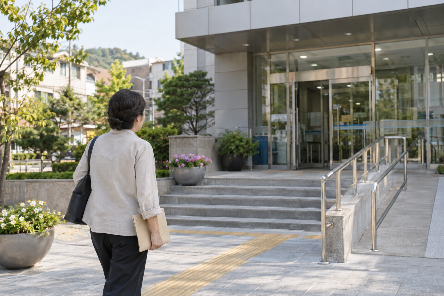 표기 없는 서류 봉투를 들고 공공서비스 건물 입구로 향하는 방문 준비 연출 사진
